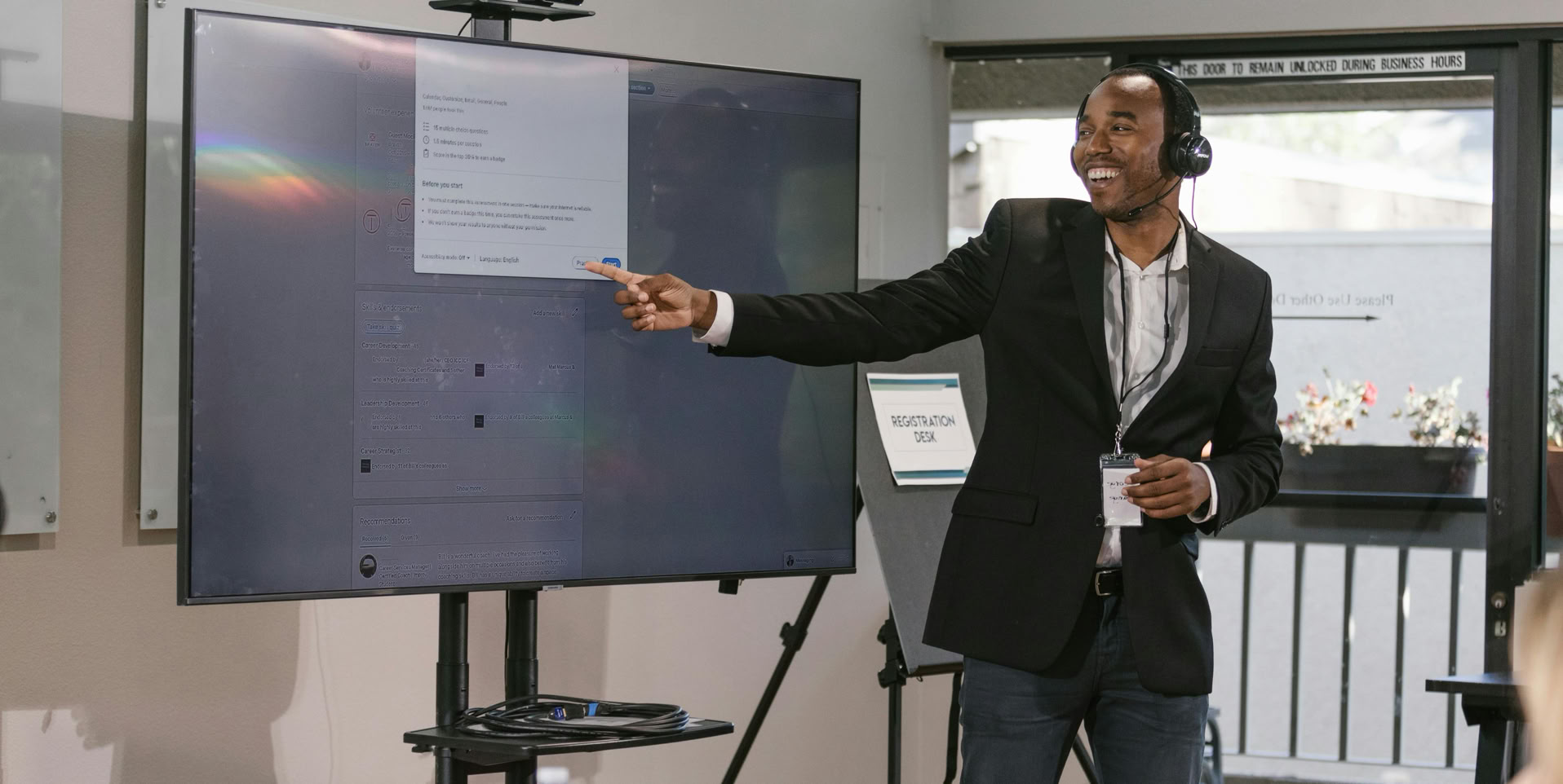 Business professional presenting with a digital screen, engaging an audience at a corporate event.