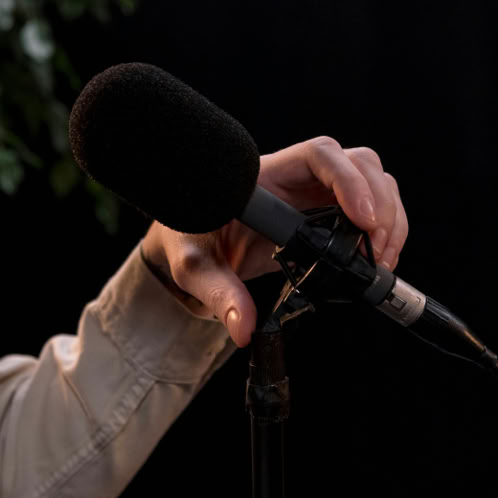 A hand adjusting a microphone stand, ideal for podcast or recording themes.