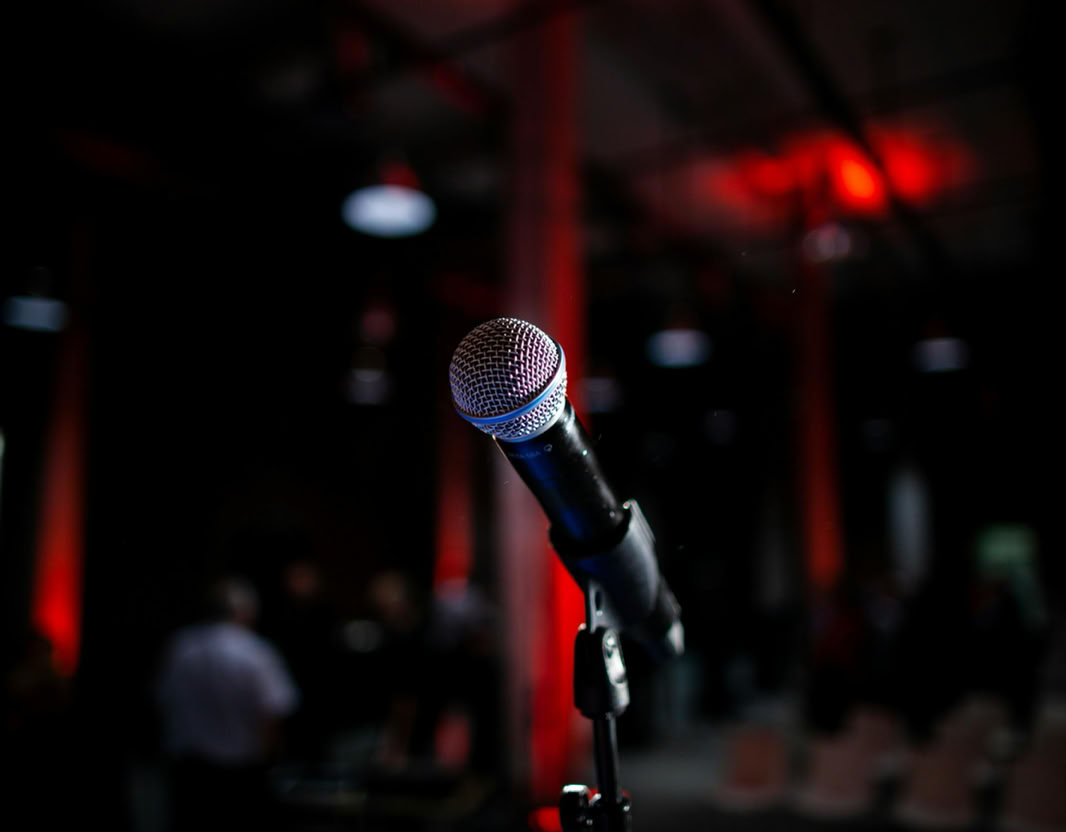 Dynamic photo of a microphone on stage with red backlighting, ideal for live performance themes.