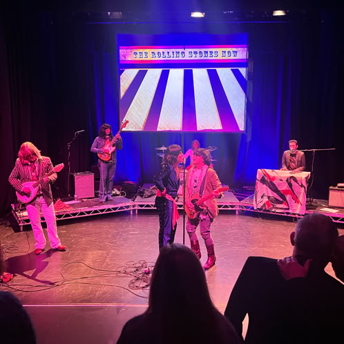 Epic nighttime concert featuring a mythical creature projection on stage with a vibrant crowd.